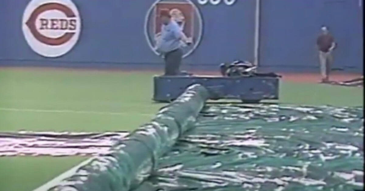 Rain Delay Masterpieces 7 An Umpire is seen behind a rolling tarpolin on a wet field